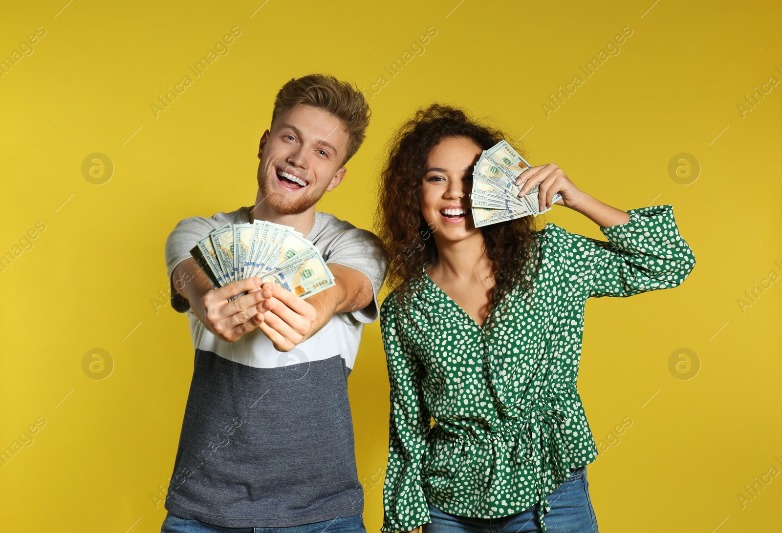 Photo of Young couple with money on color background