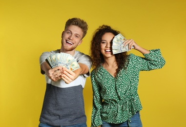 Young couple with money on color background