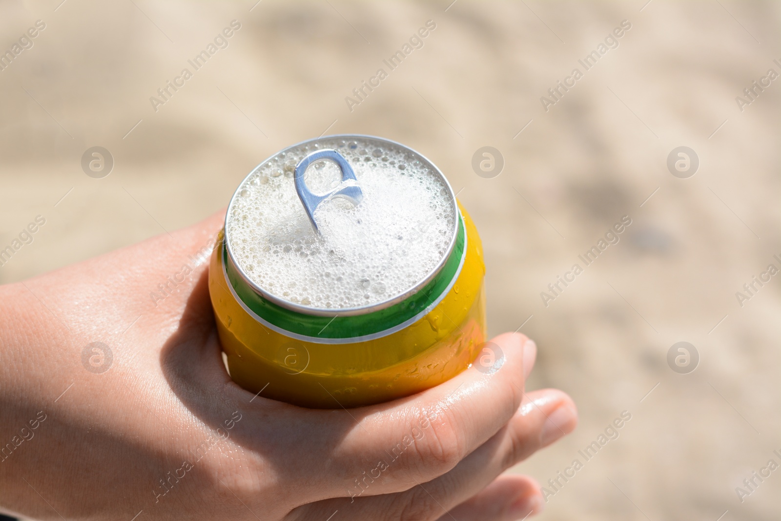 Photo of Woman holding can with sparkling drink at beach, closeup