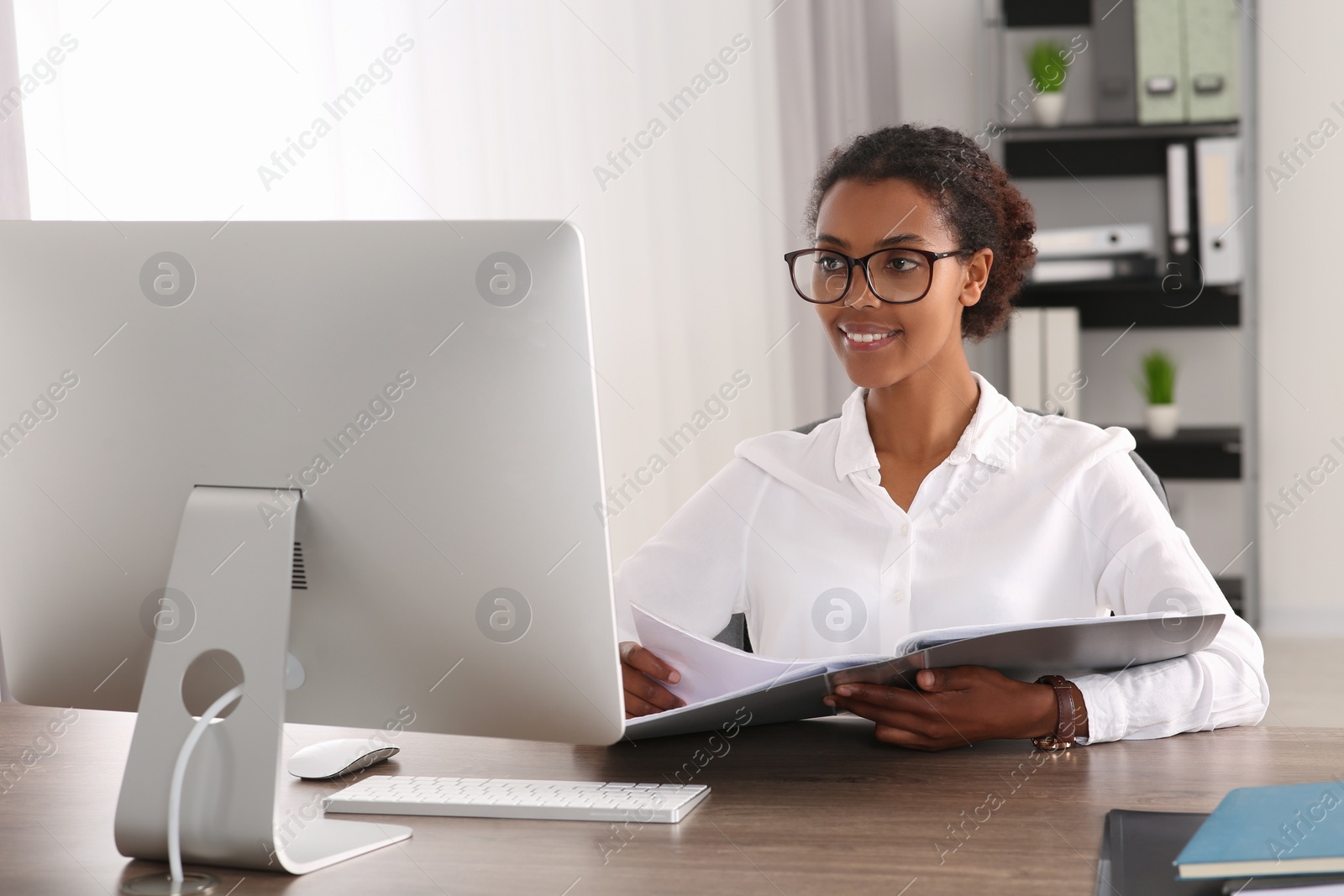 Photo of African American intern with folder working at table in office