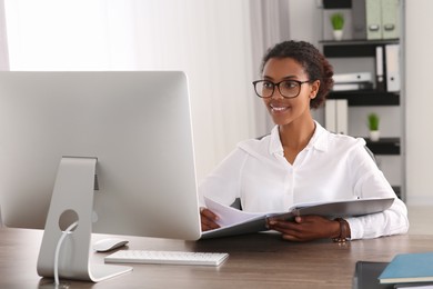 African American intern with folder working at table in office