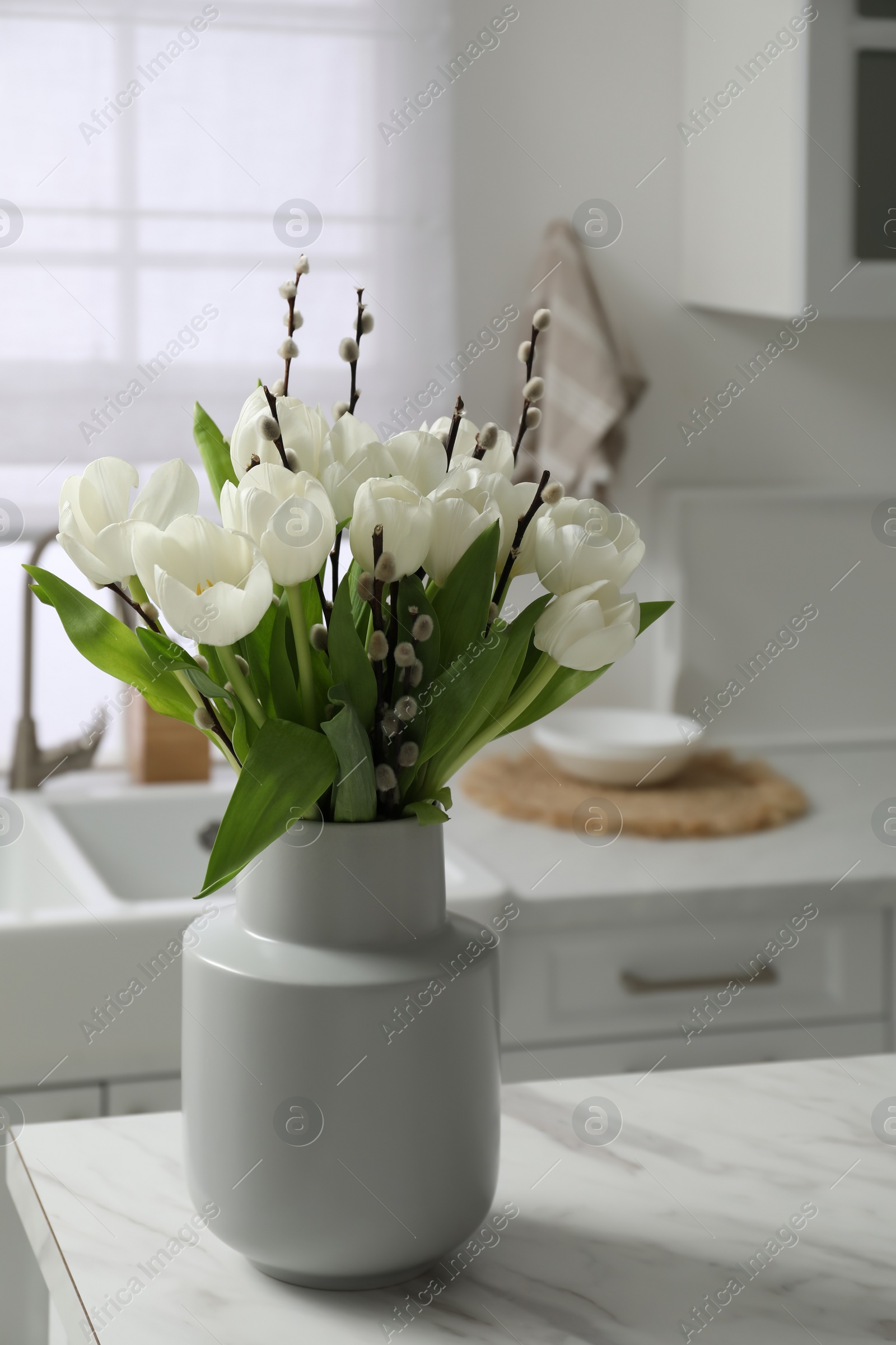 Photo of Beautiful bouquet of willow branches and tulips in vase on white table indoors