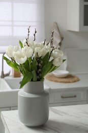 Photo of Beautiful bouquet of willow branches and tulips in vase on white table indoors