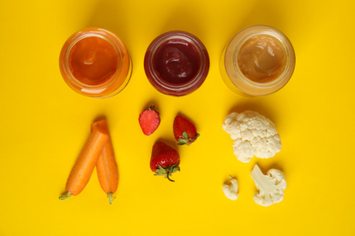 Photo of Healthy baby food in jars and fresh ingredients on yellow background, flat lay