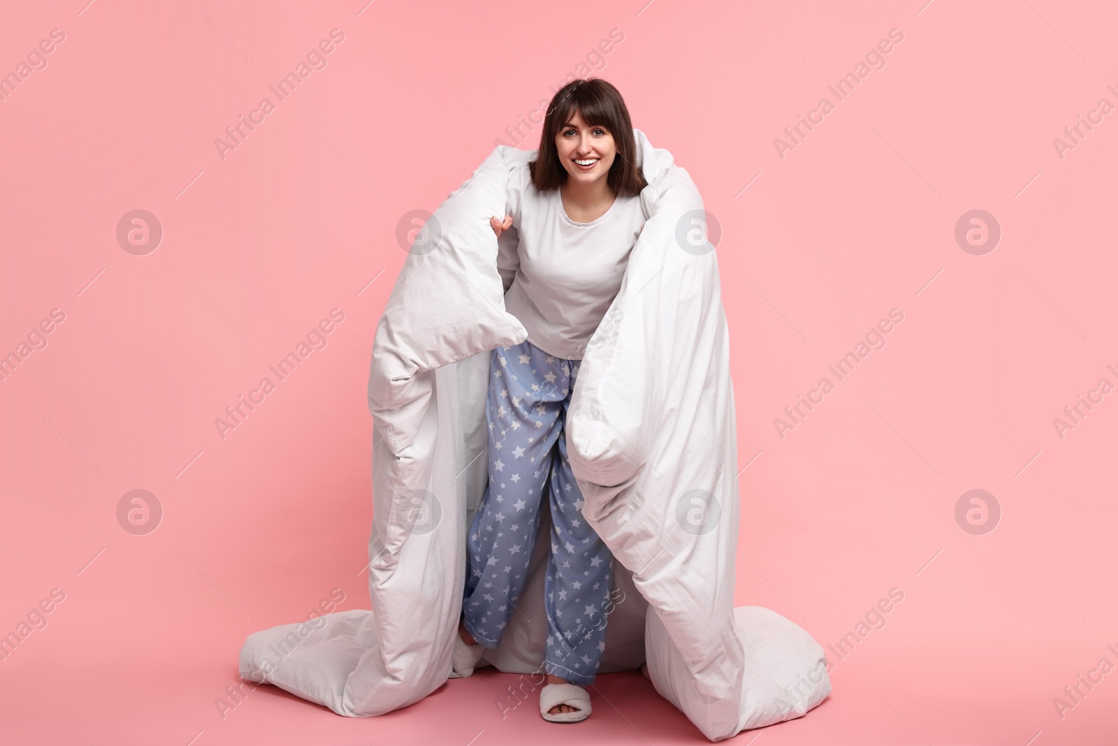 Photo of Happy woman in pyjama wrapped in blanket on pink background