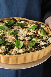 Woman holding delicious homemade spinach quiche, closeup