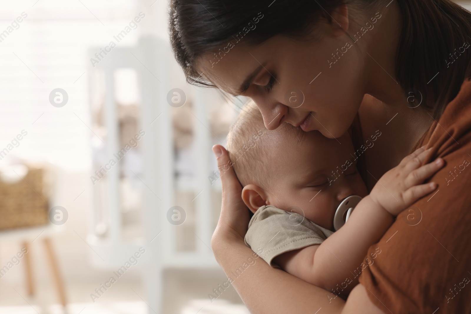 Photo of Happy young mother with her sleeping baby at home. Space for text