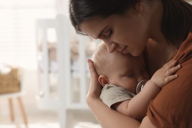 Photo of Happy young mother with her sleeping baby at home. Space for text