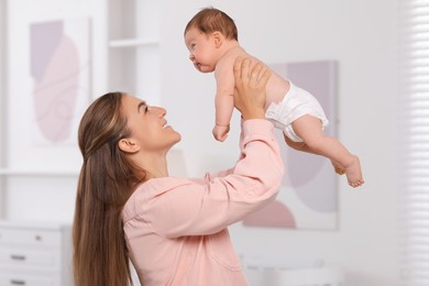 Mother holding her cute newborn baby in child's room