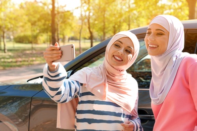 Muslim women taking selfie near car, outdoors