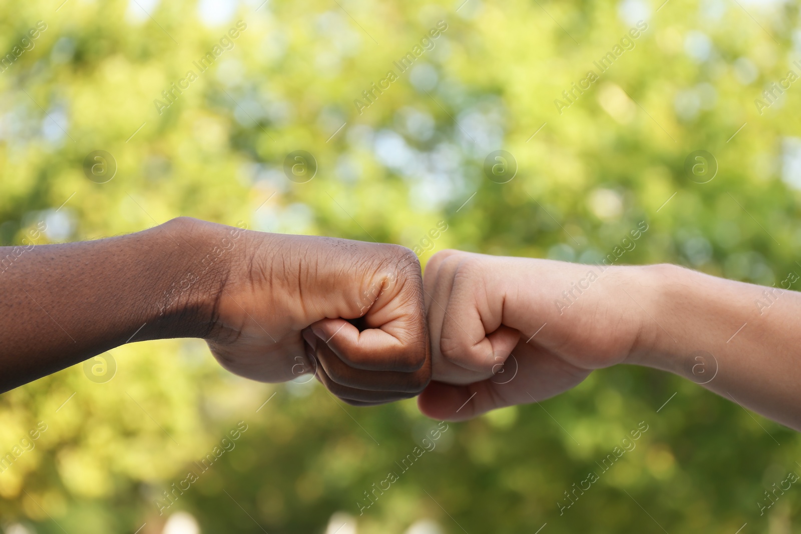 Photo of Men making fist bump outdoors, closeup view