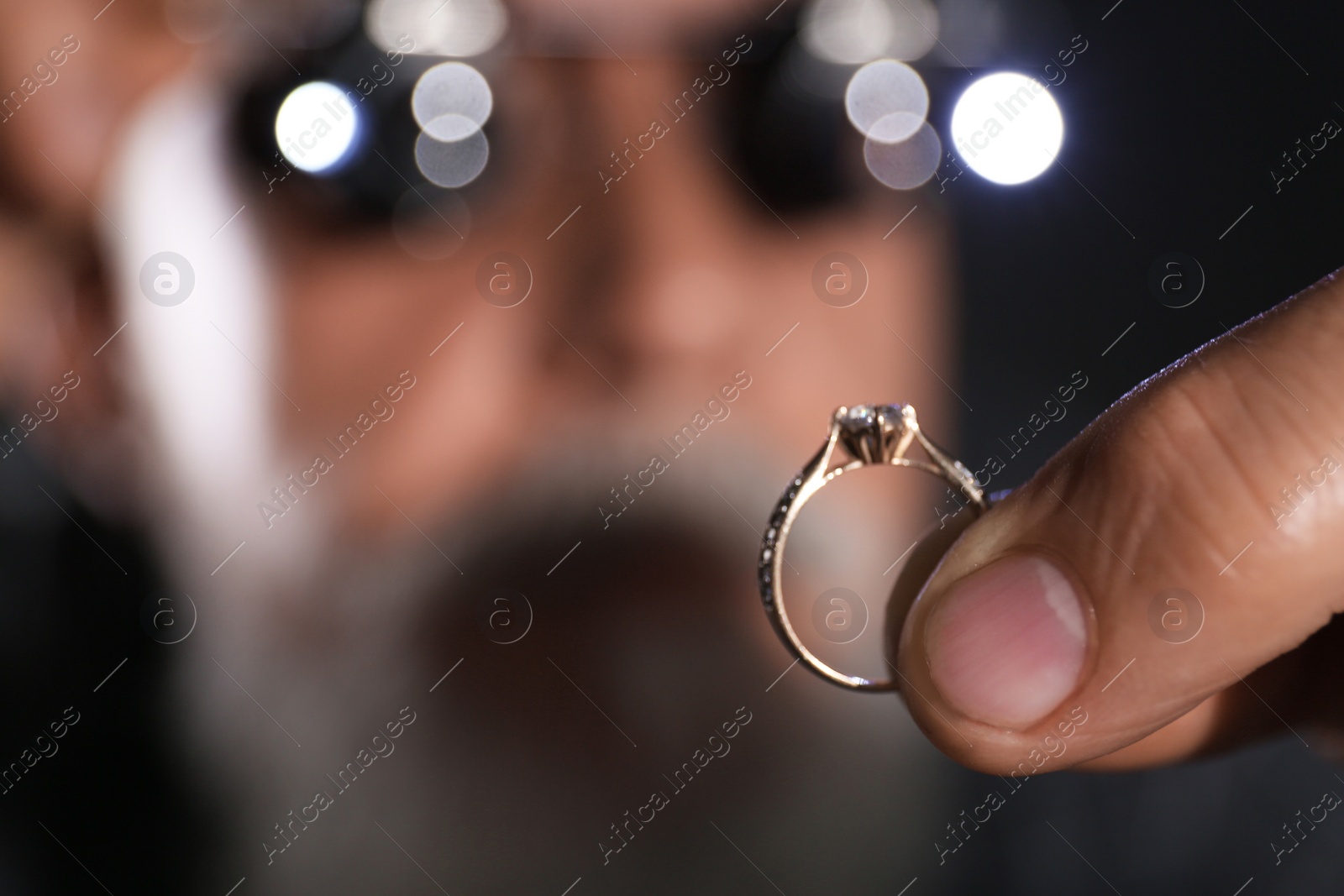 Photo of Male jeweler examining diamond ring in workshop, closeup view