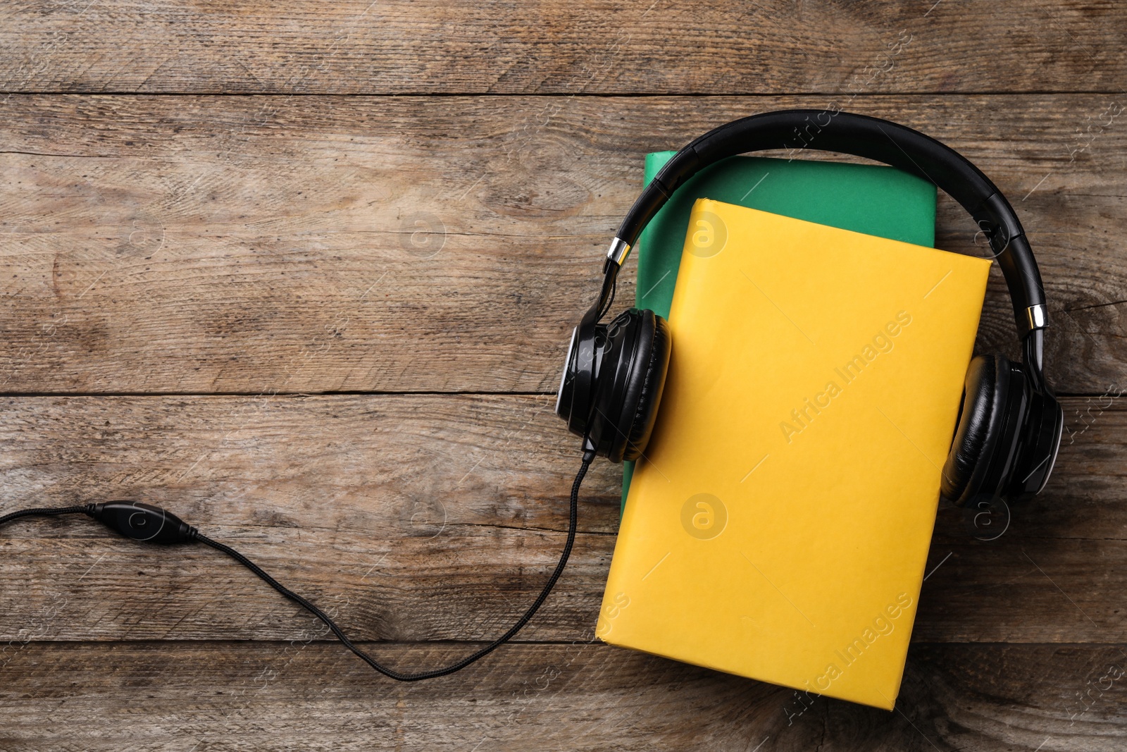 Photo of Books and modern headphones on wooden background, top view. Space for text