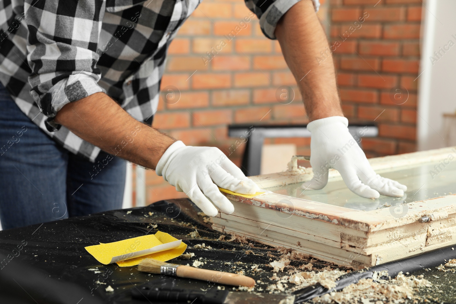 Photo of Man repairing old damaged window at table indoors, closeup