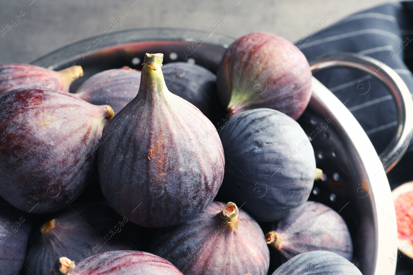 Photo of Colander with fresh ripe figs on table, closeup. Tropical fruit