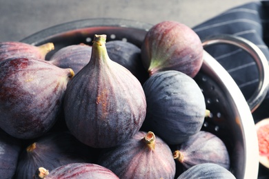 Colander with fresh ripe figs on table, closeup. Tropical fruit