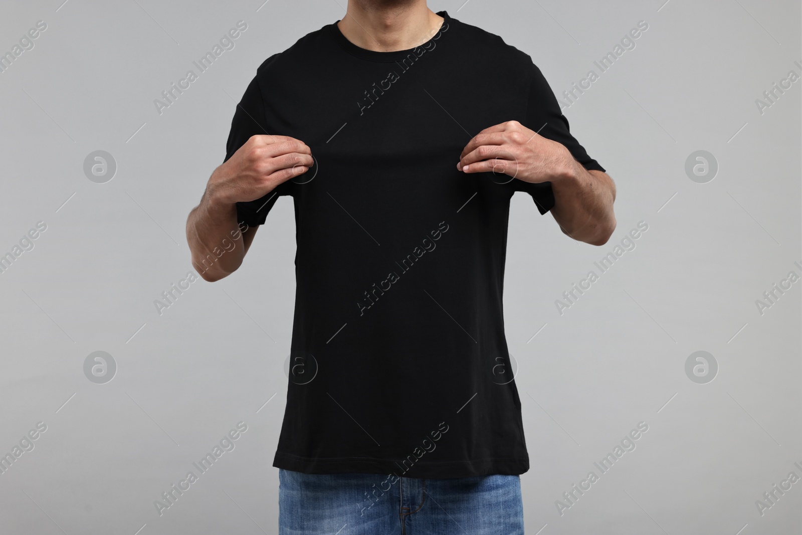Photo of Man in black t-shirt on grey background, closeup
