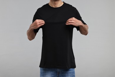 Man in black t-shirt on grey background, closeup