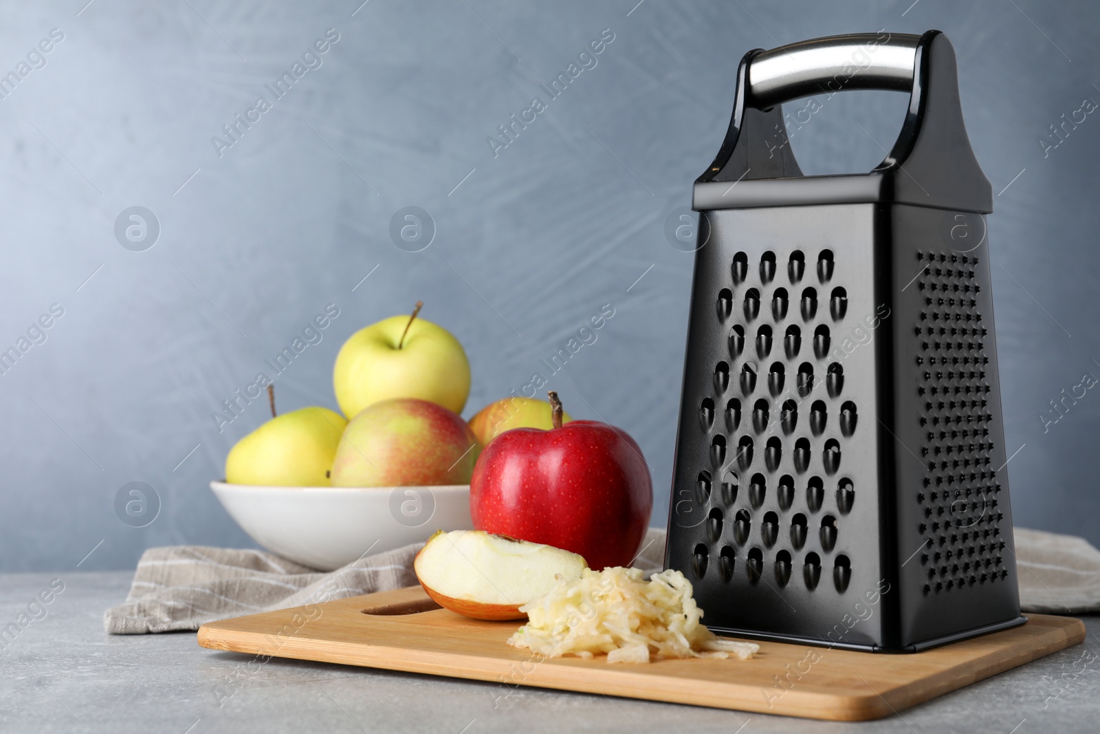 Photo of Grater and fresh ripe apples on grey table. Space for text