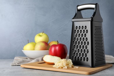 Photo of Grater and fresh ripe apples on grey table. Space for text
