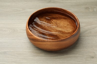 Photo of Bowl with water on wooden table, closeup