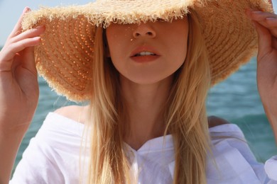 Photo of Young woman with straw hat near sea on sunny day in summer