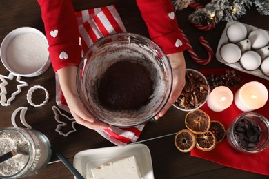 Little child making Christmas cookies at wooden table, top view