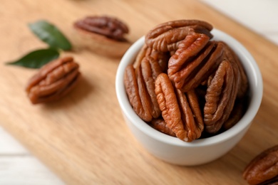 Shelled pecan nuts in bowl on wooden board. Space for text