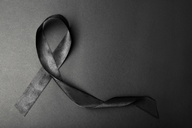 Photo of Black ribbon and space for text on dark background, top view. Funeral accessory