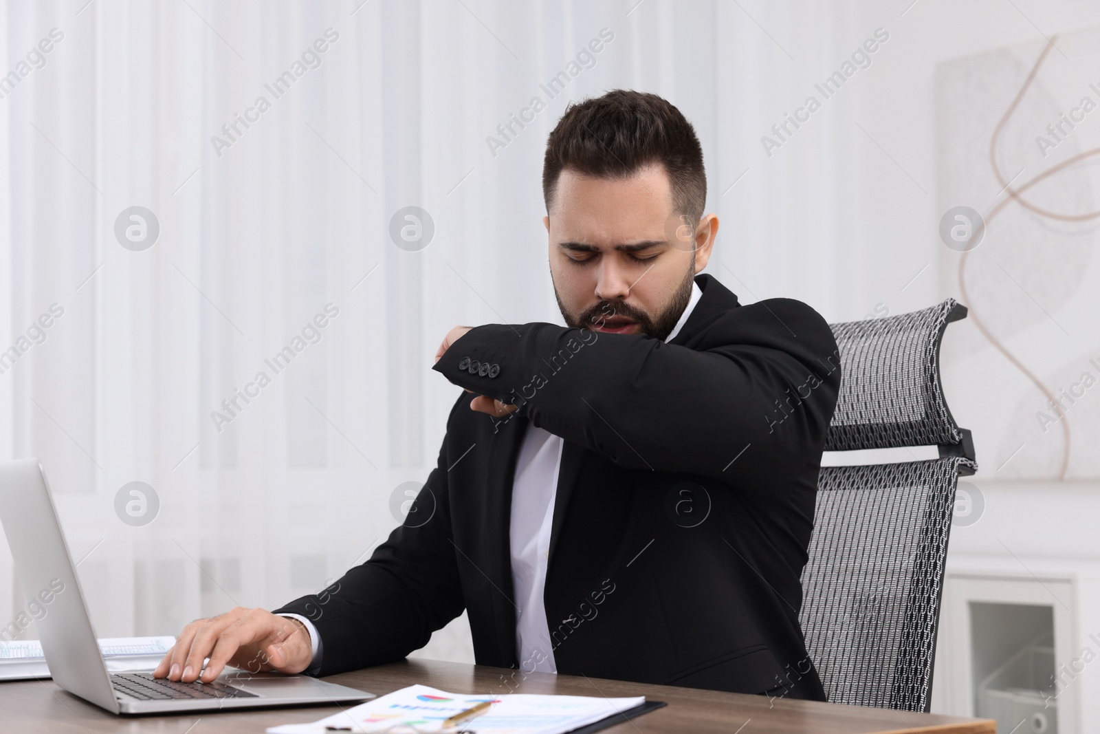 Photo of Sick man coughing at workplace in office