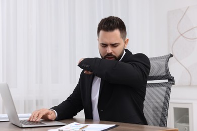 Sick man coughing at workplace in office