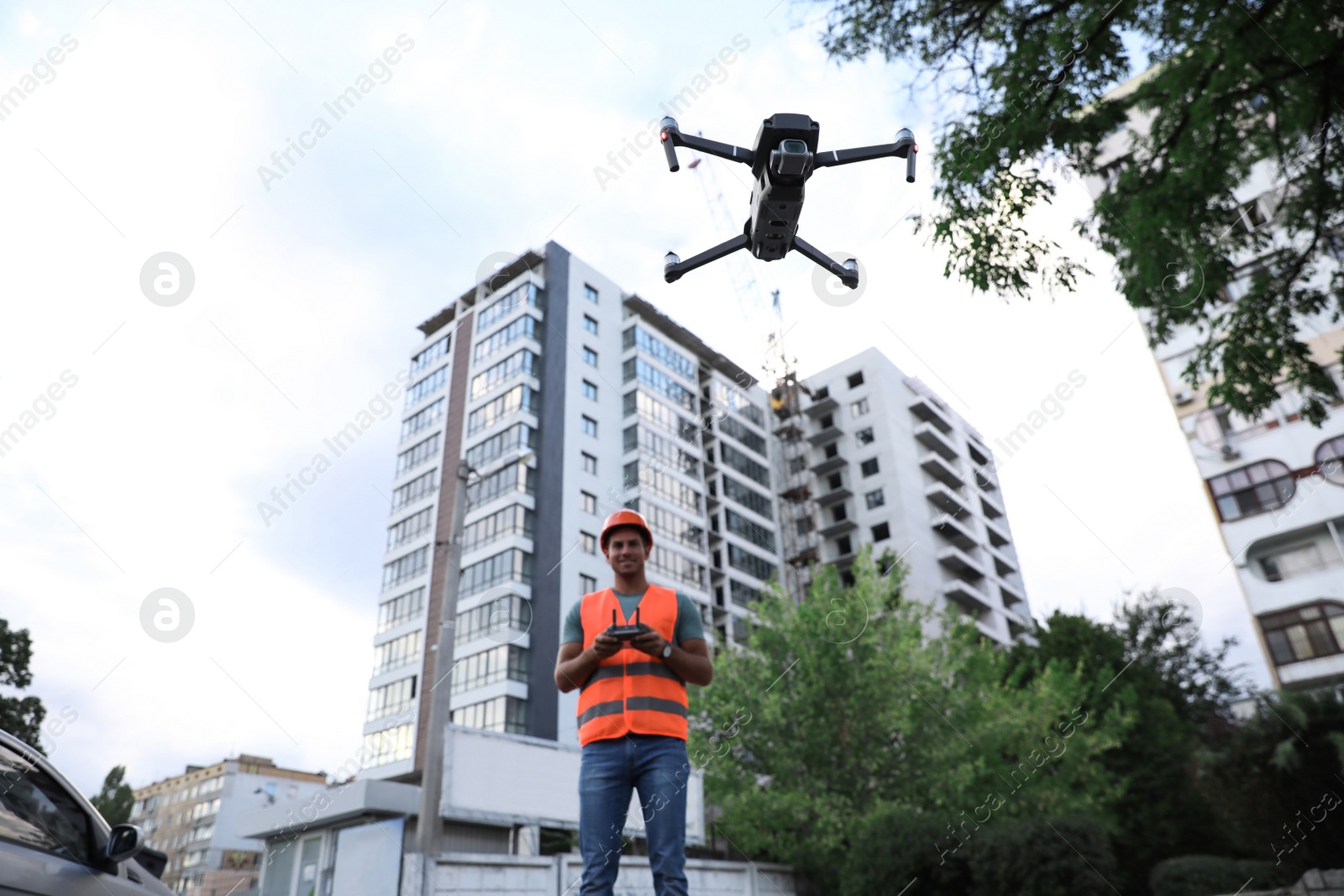 Photo of Builder operating drone with remote control at construction site. Aerial survey