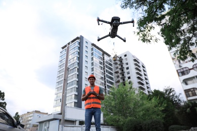 Builder operating drone with remote control at construction site. Aerial survey