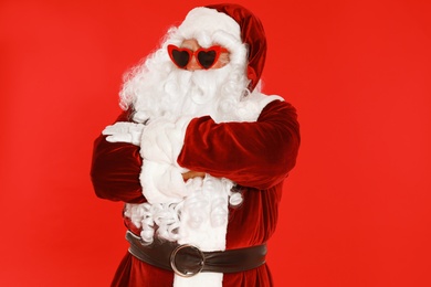 Photo of Authentic Santa Claus wearing sunglasses on red background