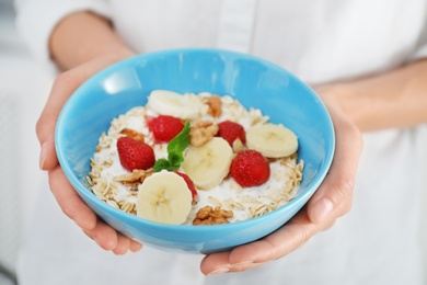 Photo of Woman holding bowl with delicious oatmeal and fruits, closeup. Healthy diet