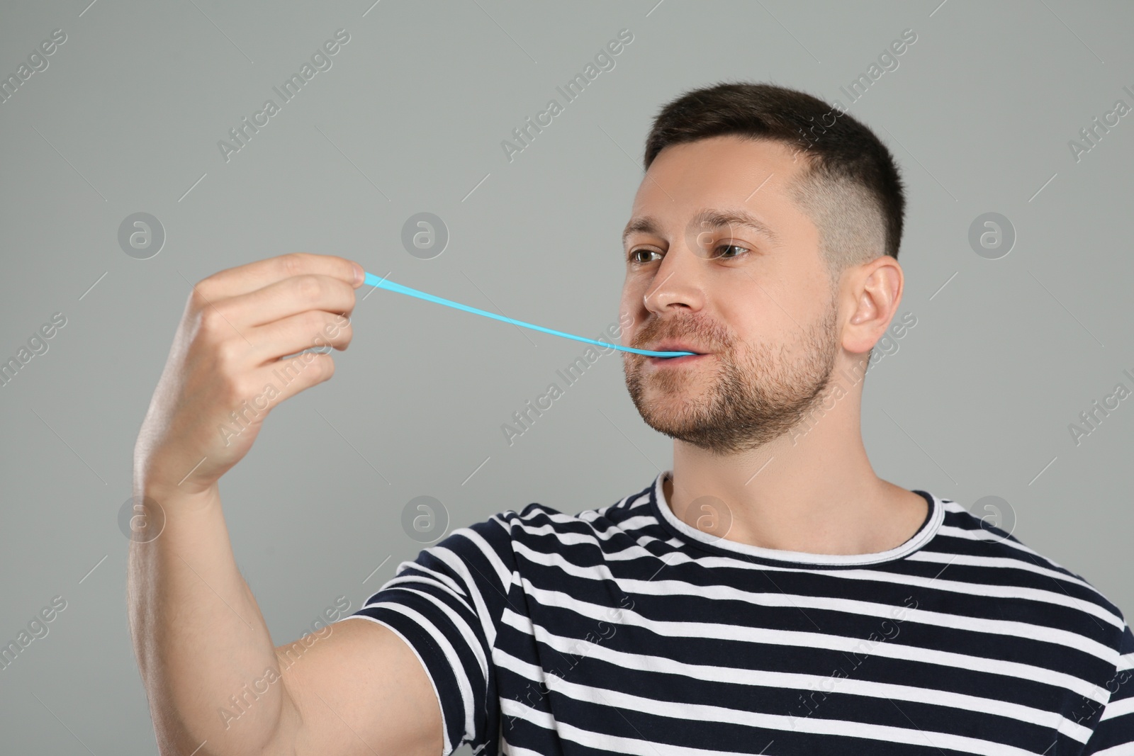 Photo of Handsome man chewing bubble gum on light grey background