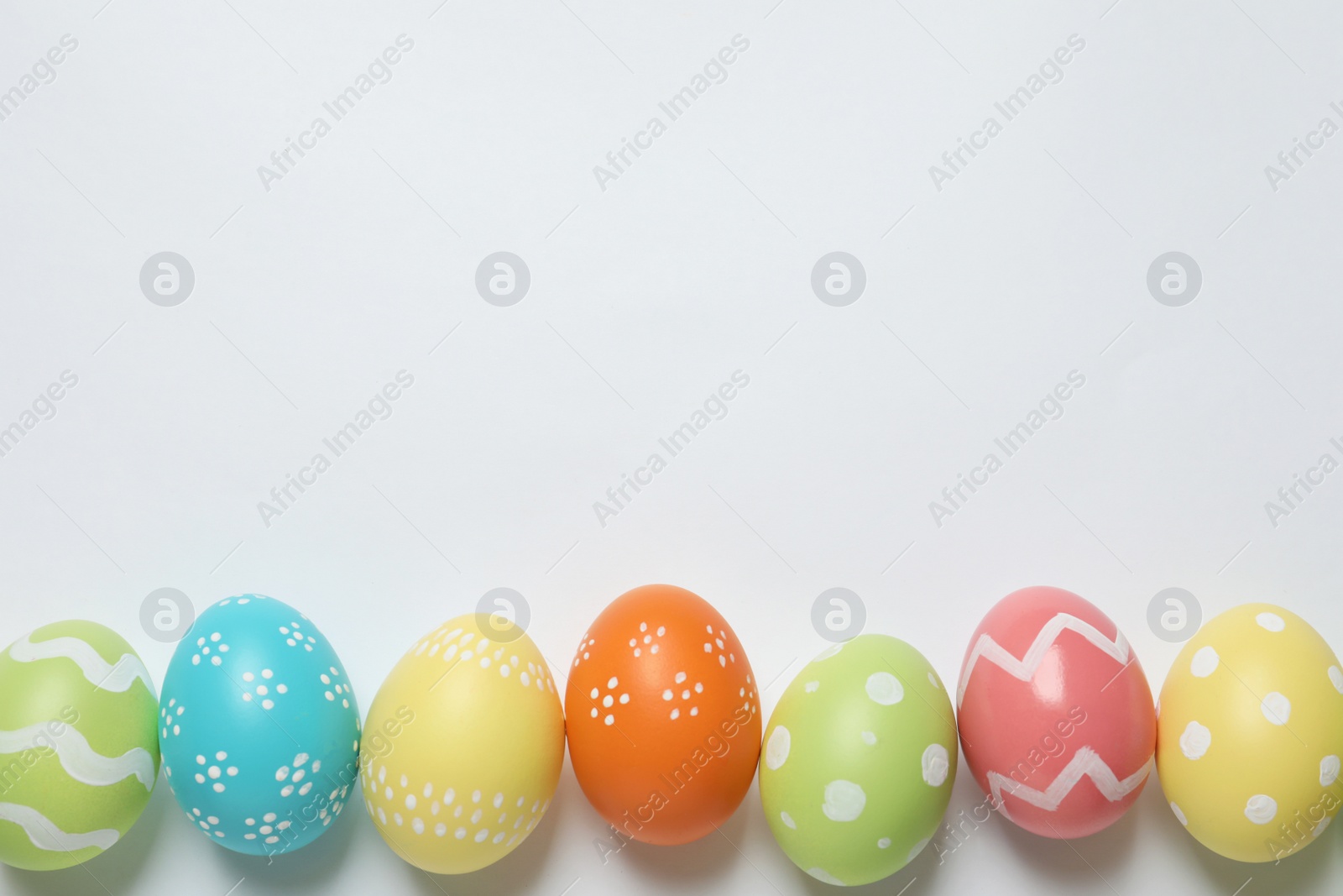 Photo of Colorful painted Easter eggs on white background, top view