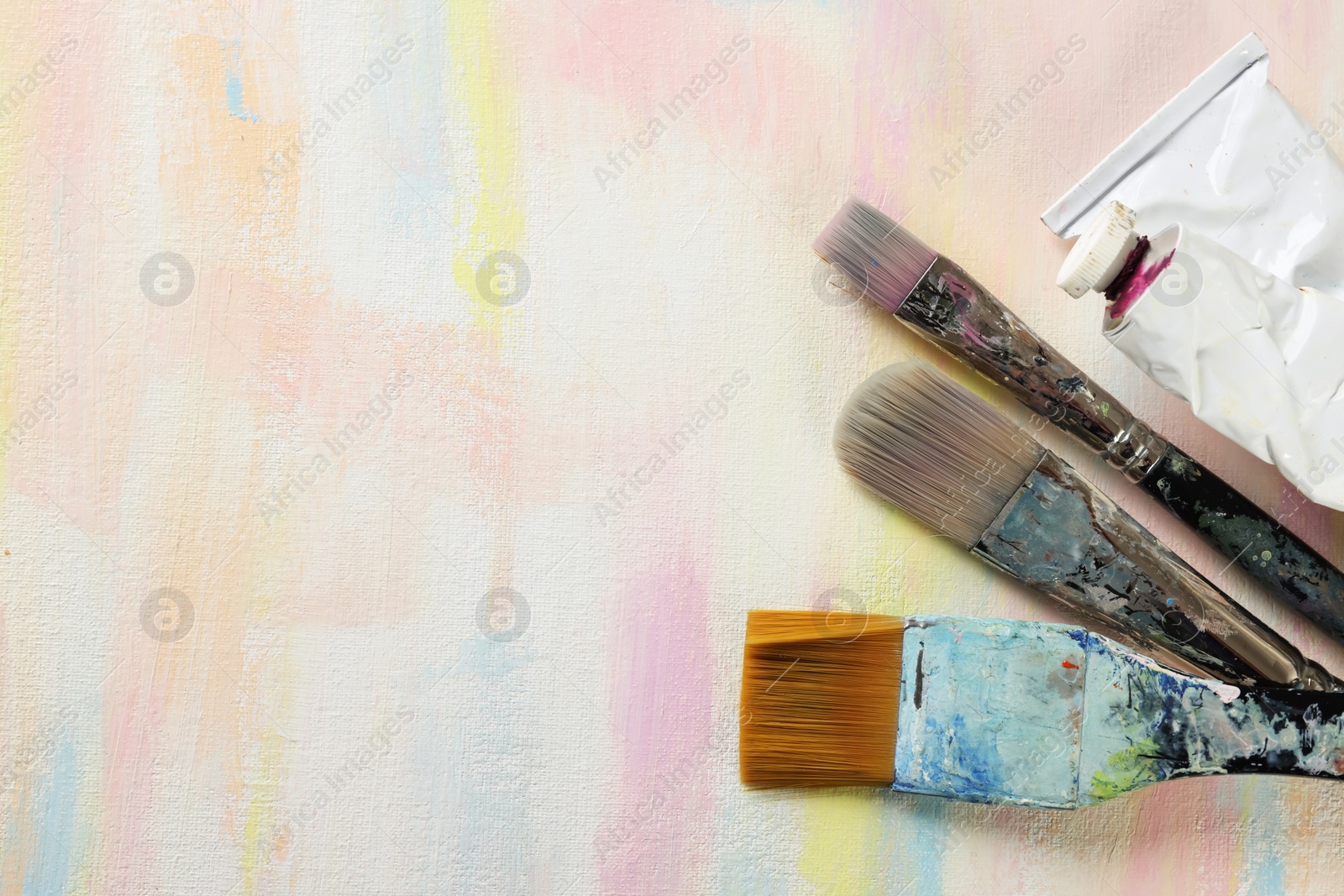 Photo of Set of brushes and paints on abstract picture, flat lay. Space for text