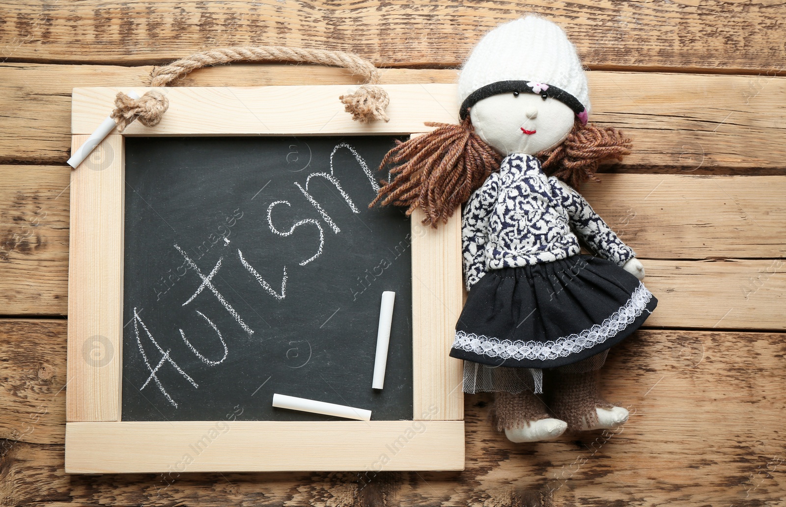 Photo of Chalkboard with word "Autism" and doll on wooden background