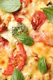 Photo of Tasty quiche with cheese, tomatoes and basil leaves as background, top view