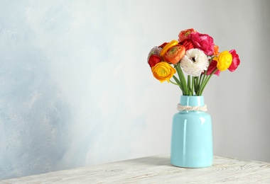 Photo of Vase with beautiful ranunculus flowers on table. Space for text