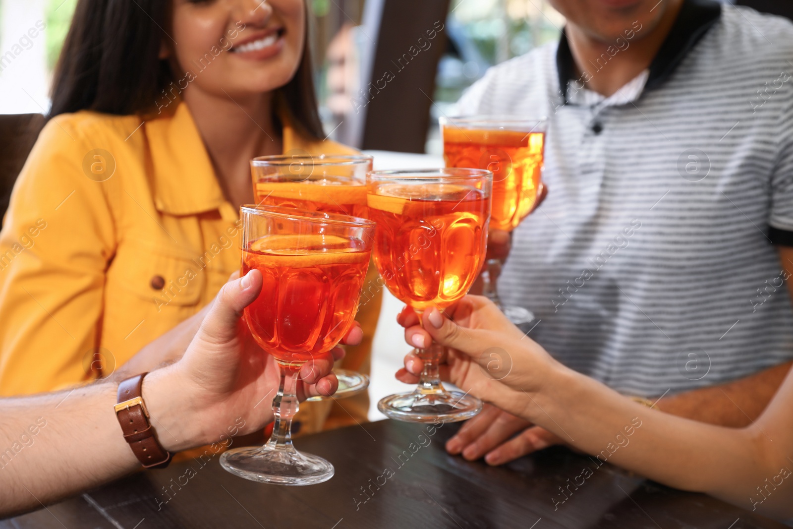 Photo of Friends with Aperol spritz cocktails resting together at restaurant, closeup