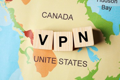 Photo of Acronym VPN (Virtual Private Network) made of wooden cubes on world map, flat lay