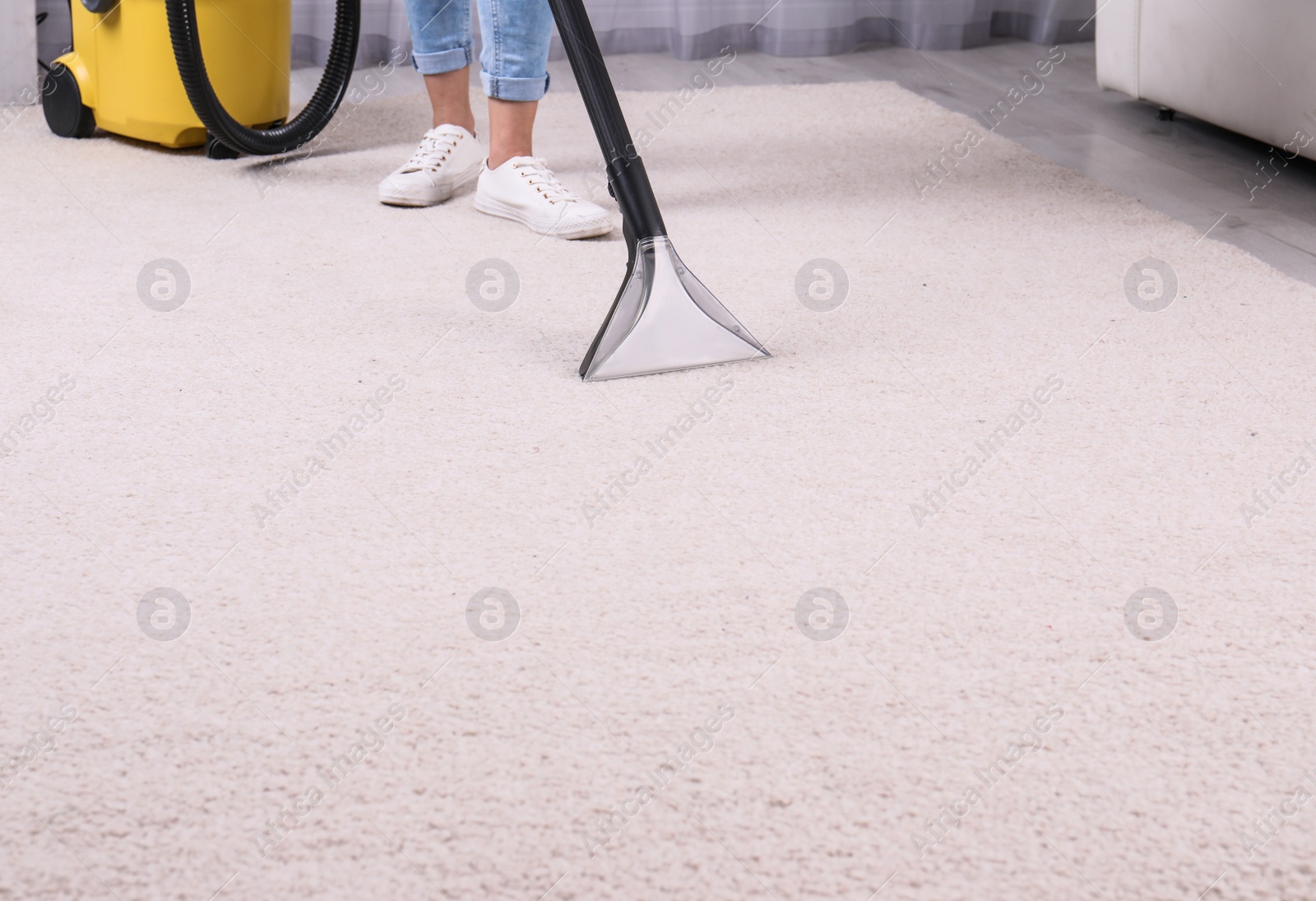 Photo of Woman cleaning carpet with vacuum cleaner, closeup. Space for text