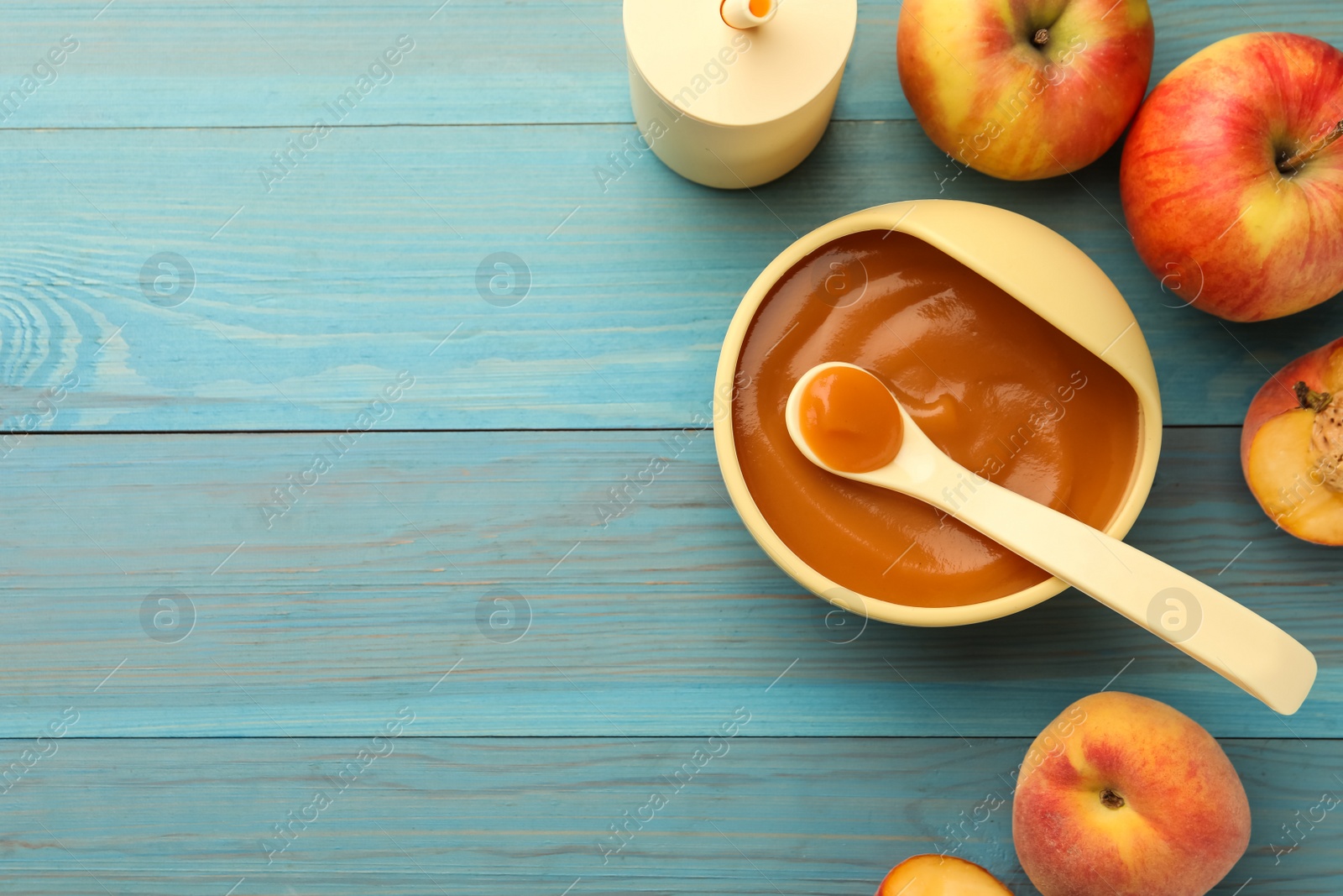 Photo of Tasty pureed baby food and ingredients on light blue wooden table, flat lay. Space for text