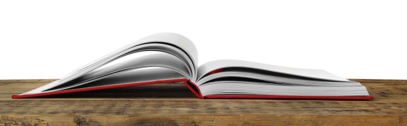 Photo of Open book with red cover on wooden table against white background