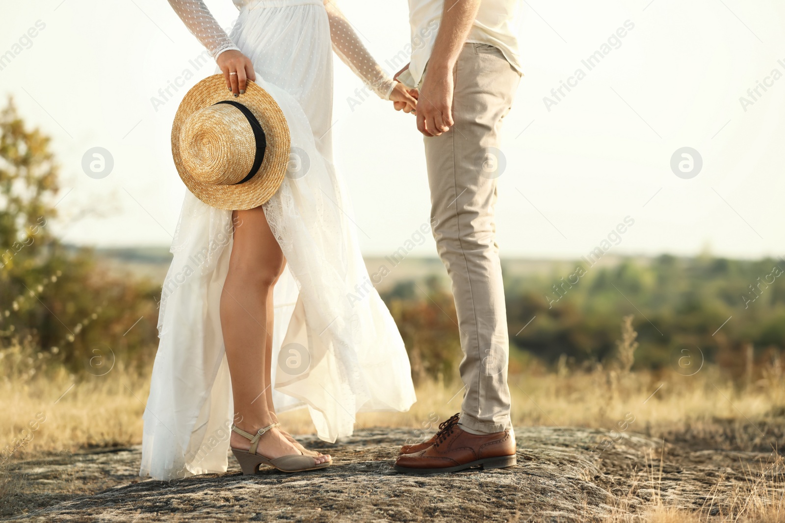 Photo of Happy newlyweds with straw hat outdoors, closeup