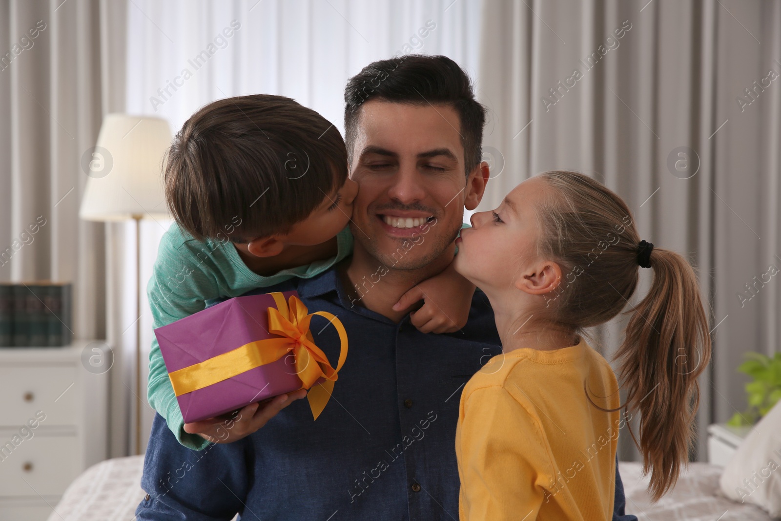 Photo of Man receiving gift for Father's Day from his children at home