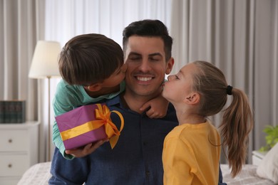 Man receiving gift for Father's Day from his children at home