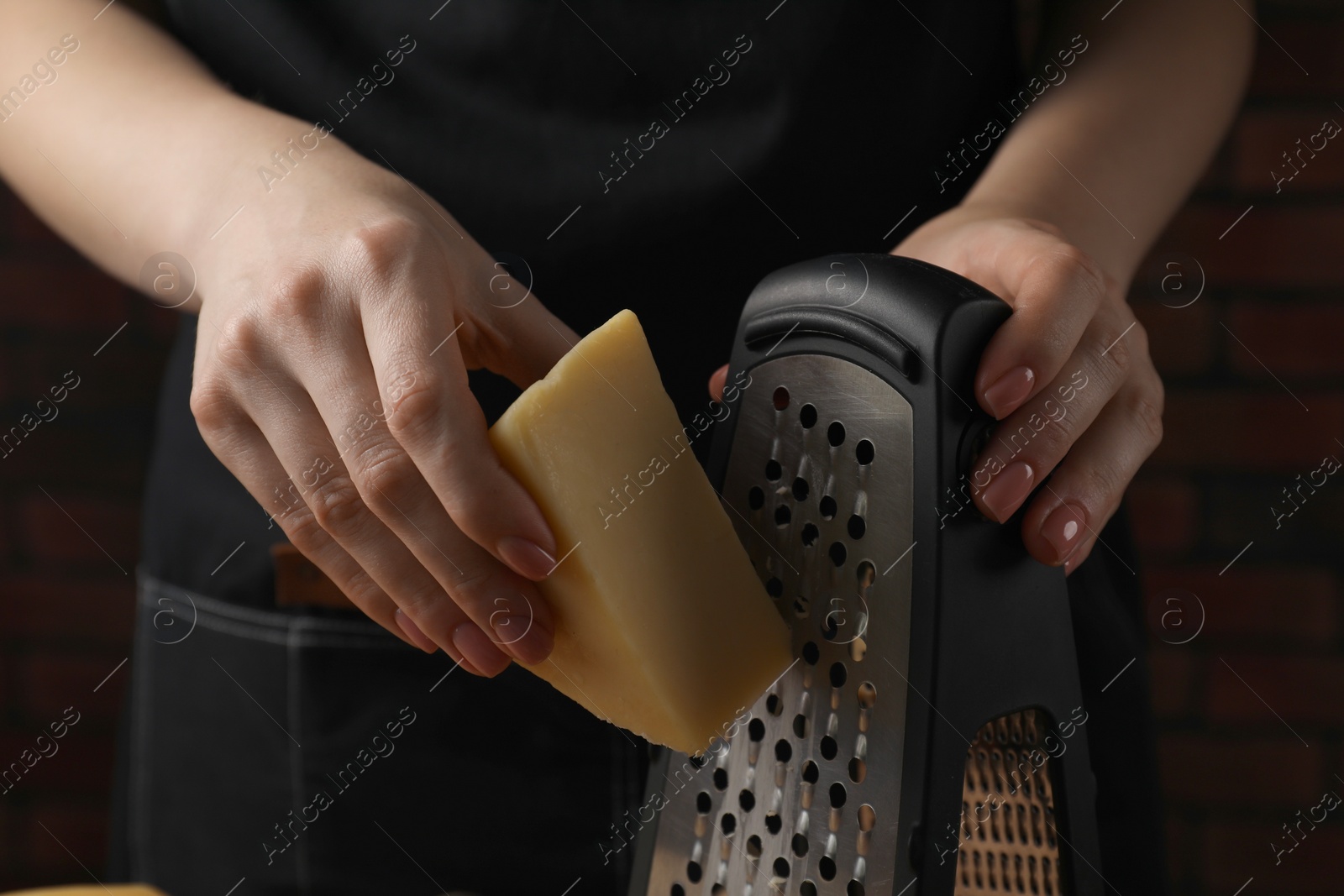 Photo of Woman grating cheese at wooden table, closeup